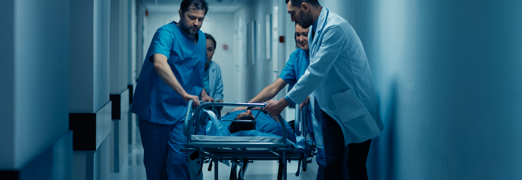 Vårdpersonal transporterar snabbt en patient på bår genom en sjukhuskorridor vid ett akuttillstånd.